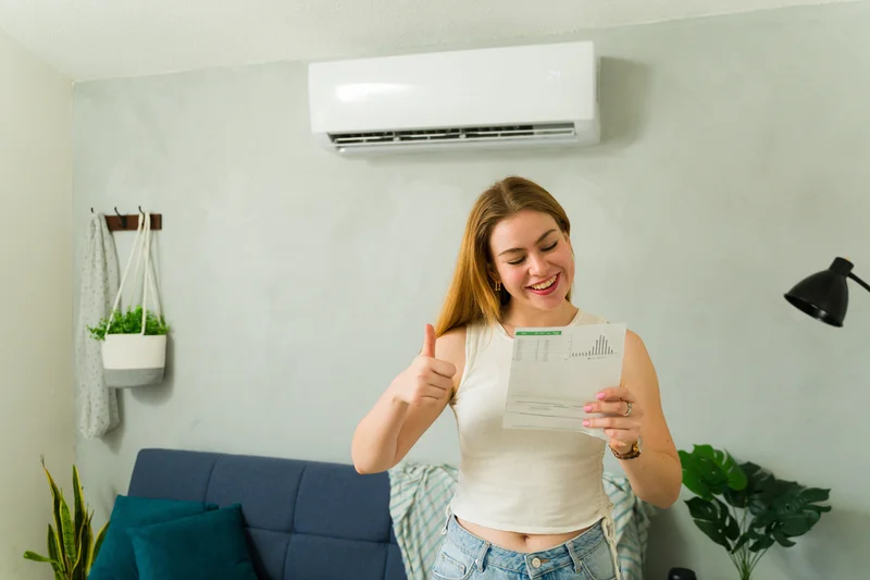 Woman looking at a bill with a mini split on the back wall